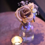 Tisch mit Rose in kleiner Vase und Teelicht davor